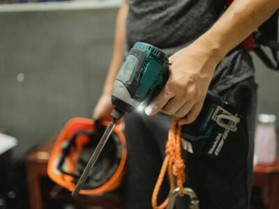 Mesin Bor Impact Cordless - A worker holding a power drill and helmet, ready for maintenance tasks.